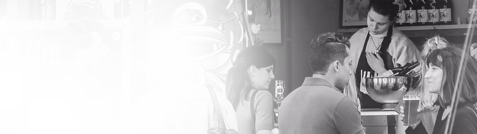 Imagen en blanco y negro de un restaurat, donde se ven varias personas interactuando entre sí cerca de un mostrador